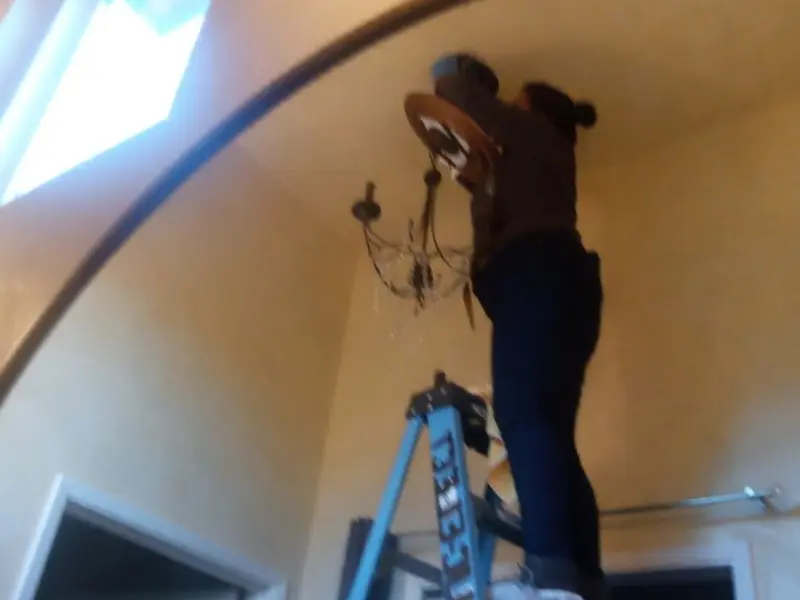 Electrician installing a chandelier in a Fort Pierce residence